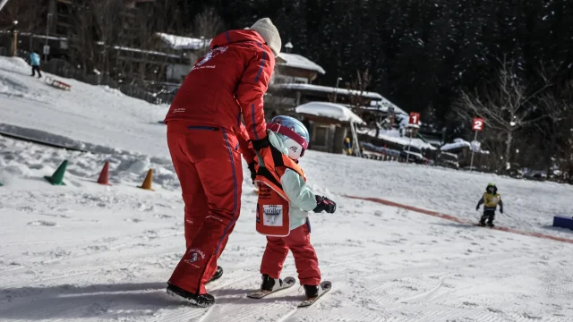 Kind lernt Skifahren mit einem Lehrer.