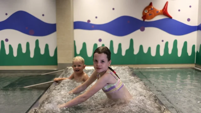 Kinder im Wasserbereich mit bunter Wandgestaltung.