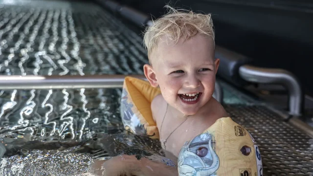 Fröhliches Kind im Wasser mit Schwimmflügeln.