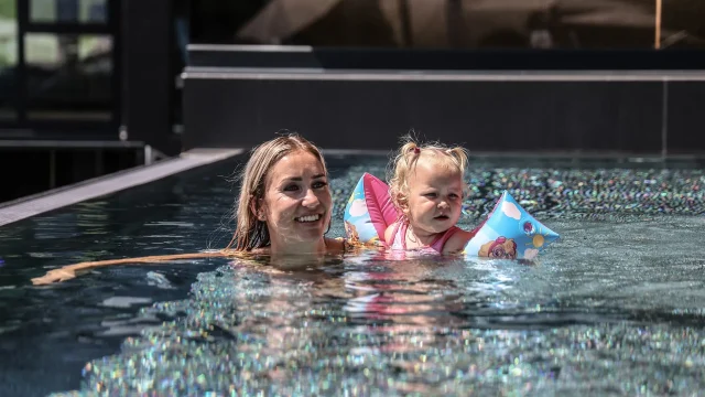 Frau und Kind im Wasser mit Schwimmhilfen