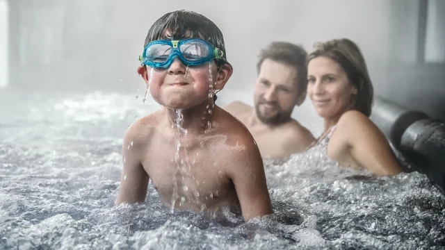 Junge mit Schwimmbrille im Wasser spritzt.