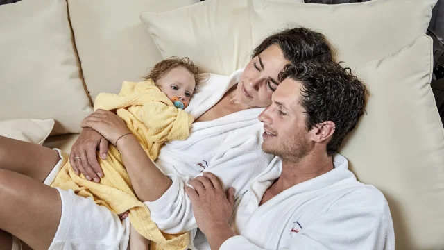 Familie entspannt zusammen auf dem Sofa.