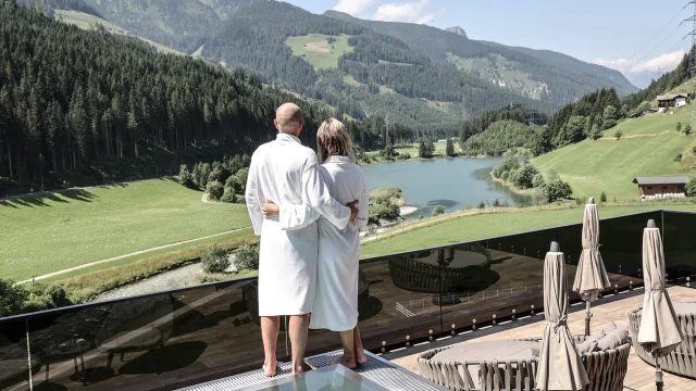 Paar in Bademänteln überblickt Landschaft.