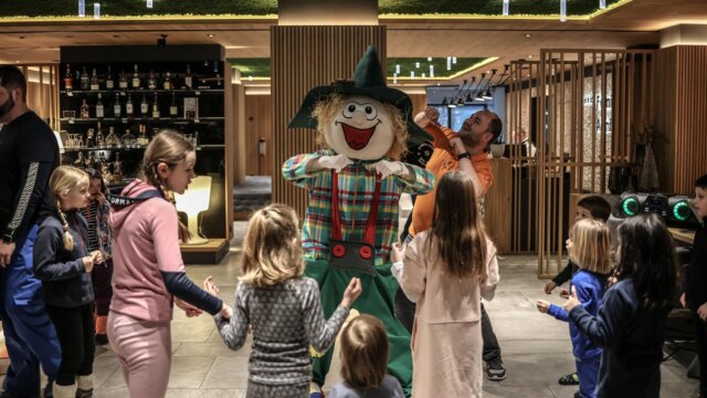 Kinder tanzen mit einem lustigen Maskottchen.