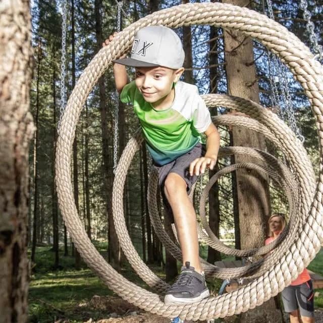 Junge spielt auf Seilringe im Wald.