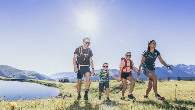 Familie wandert an sonnigem Tag in den Bergen.