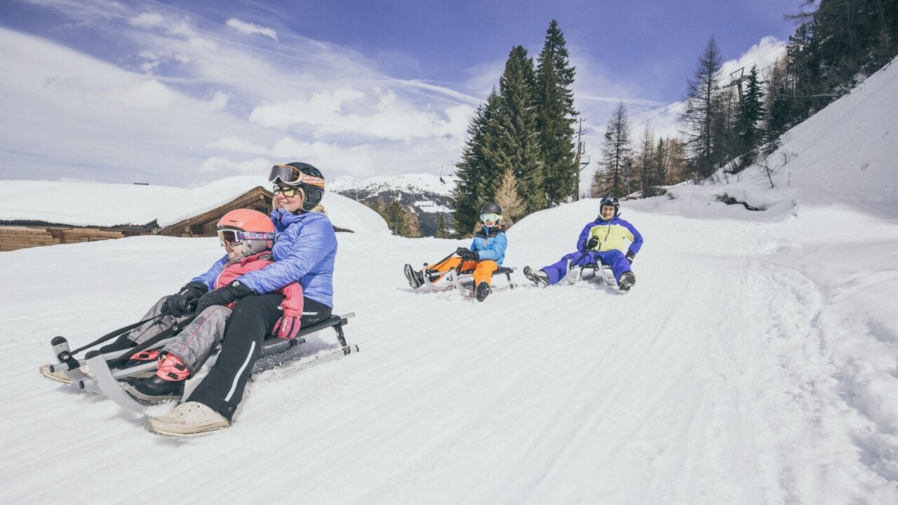 Familie fährt mit dem Schlitten im Schnee.