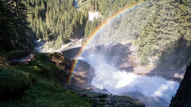 Wasserfall mit Regenbogen und grünen Wäldern