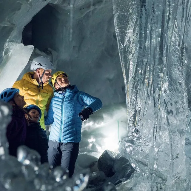 Familie erkundet eine beeindruckende Eishöhle.