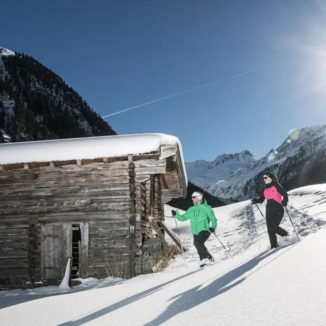 Skifahrer in verschneiter Berglandschaft vor Hütte