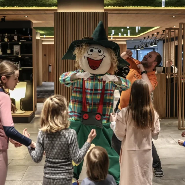 Kinder tanzen mit einem lustigen Maskottchen.