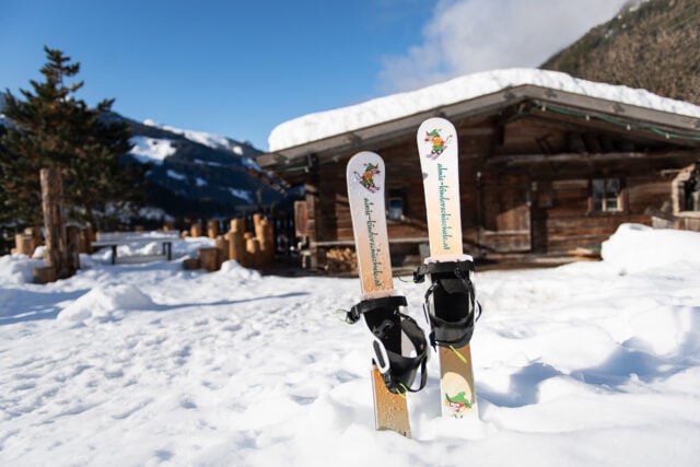 Ski stehen im Schnee vor einer Hütte.