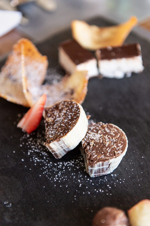 Leckere Desserts auf einem schwarzen Teller.