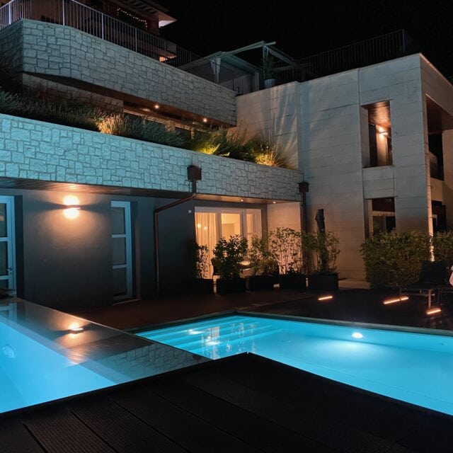 Moderne Architektur mit beleuchtetem Pool bei Nacht