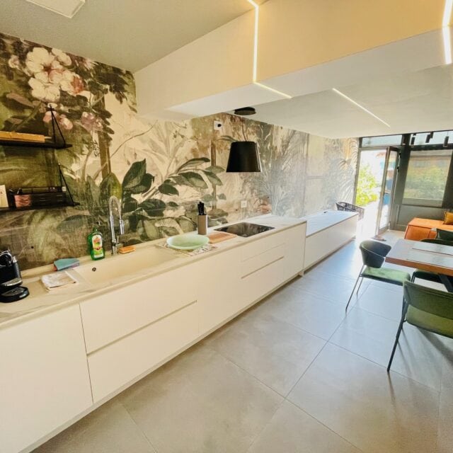 Moderne Küche mit Pflanzenwand und gemütlichem Essbereich.