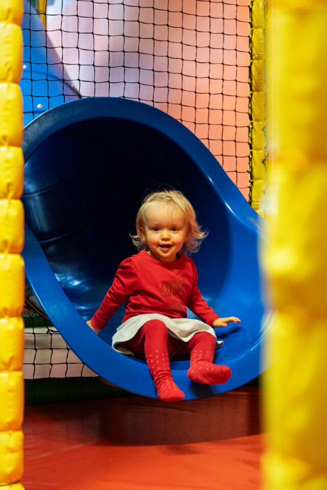 Kleines Kind rutscht fröhlich die Rutsche hinunter.