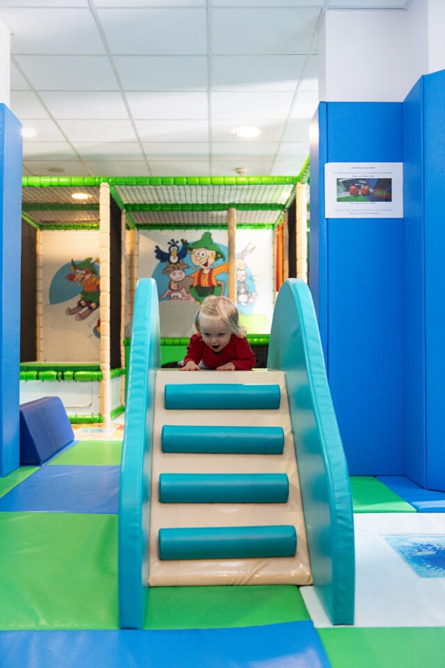 Kleines Kind spielt auf einer Rutsche.