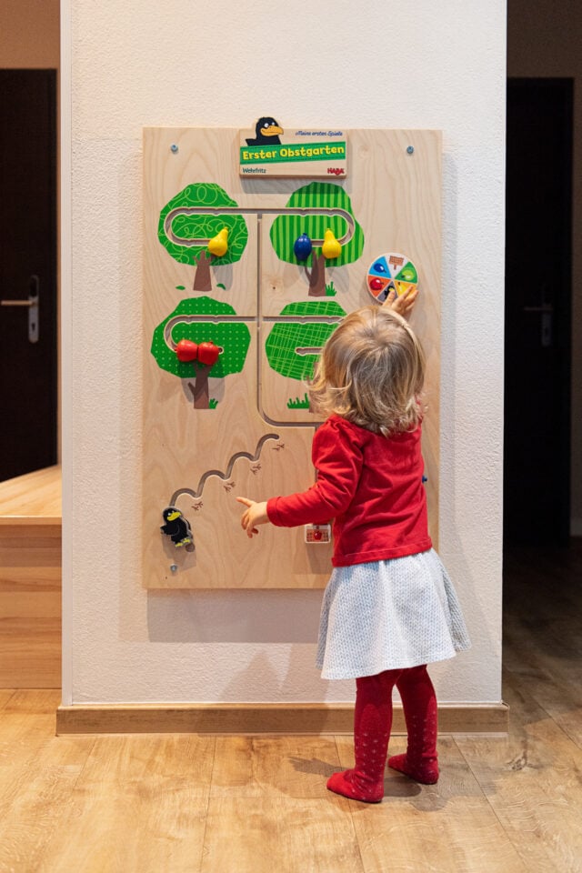 Kind spielt mit einem Holzspielzeug im Spielzimmer.