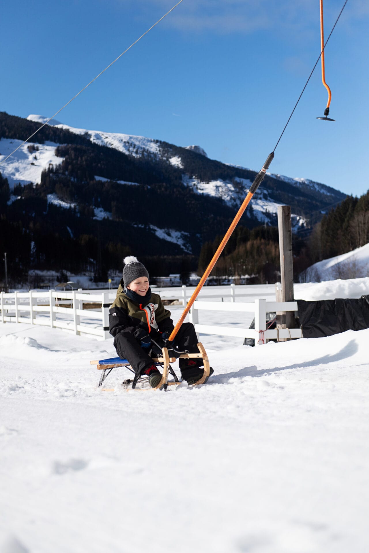 Junge auf einem Schlitten im Schnee.