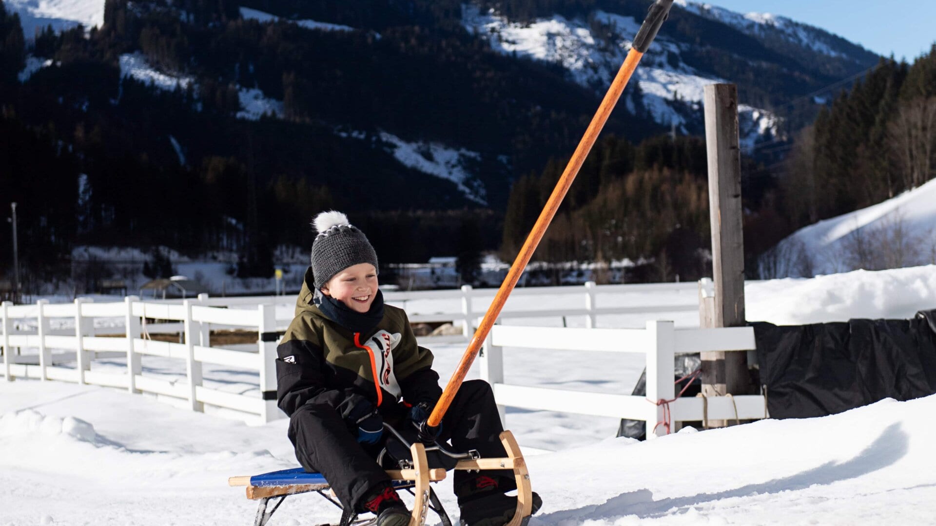 Junge auf einem Schlitten im Schnee.