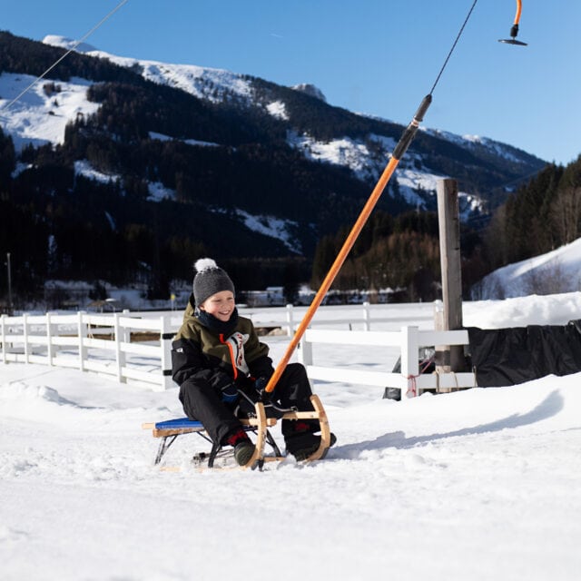 Junge auf einem Schlitten im Schnee.