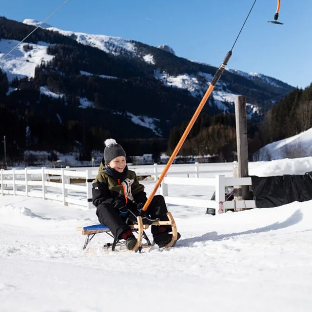 Junge auf einem Schlitten im Schnee.