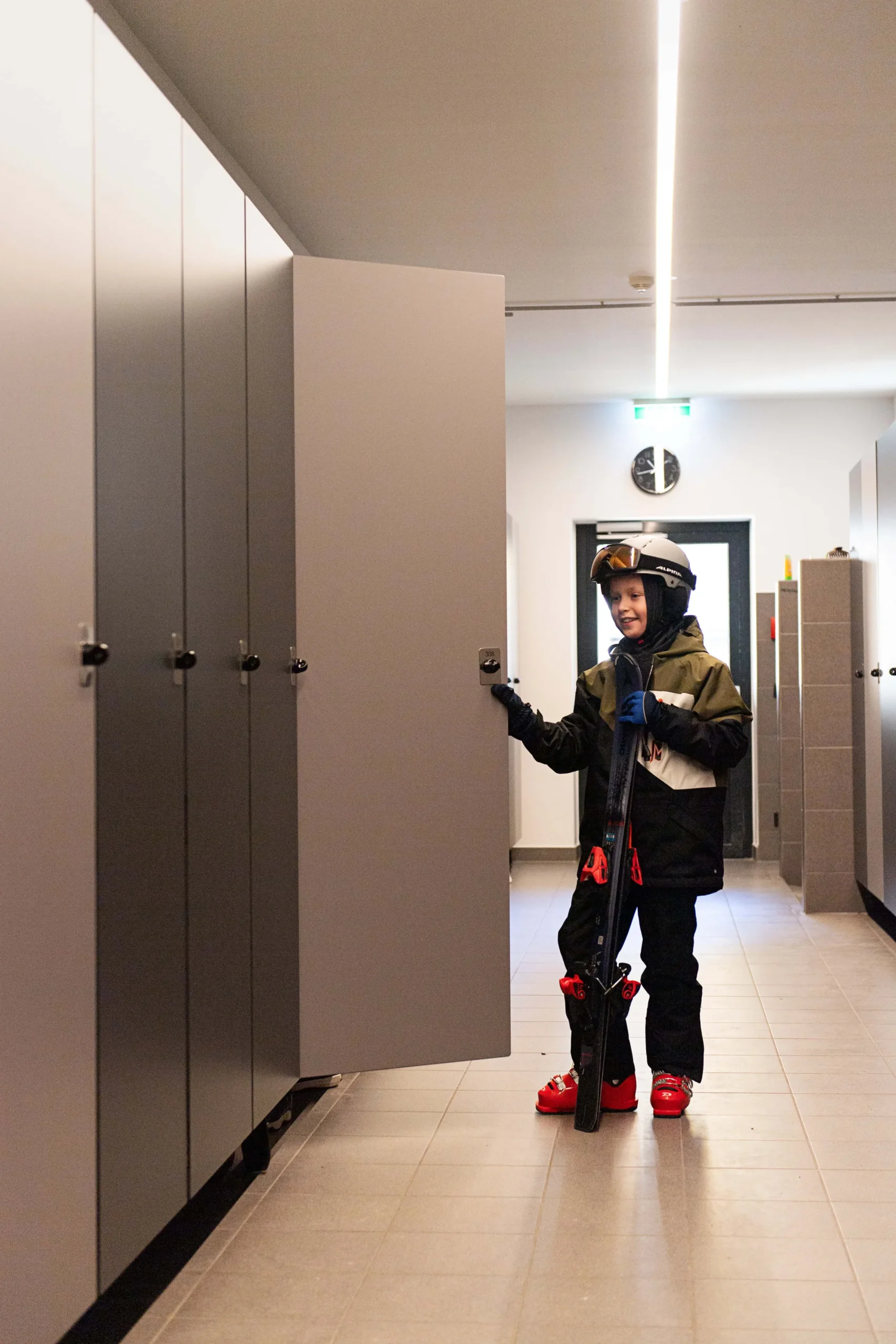 Junge mit Ski in einem Umkleideraum