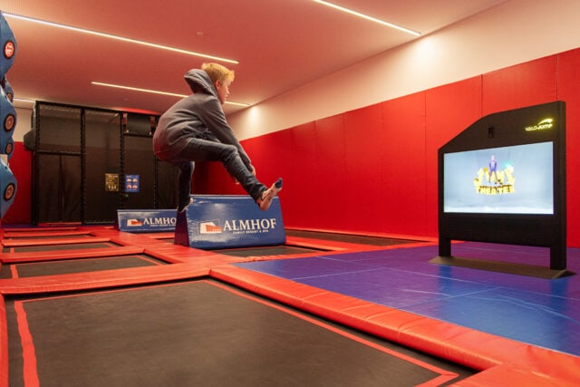 Kind springt auf Trampolin mit Bildschirm im Hintergrund