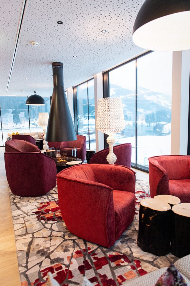 Gemütliche Lounge mit roten Sesseln und Fenstern.