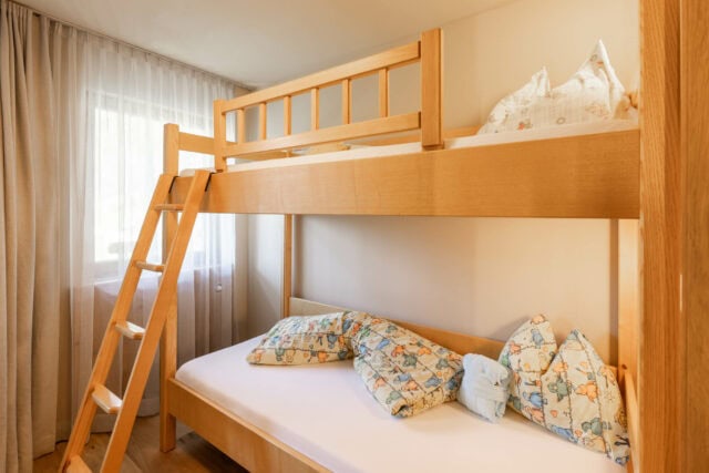Helles Kinderzimmer mit Hochbett und Kuschelkissen