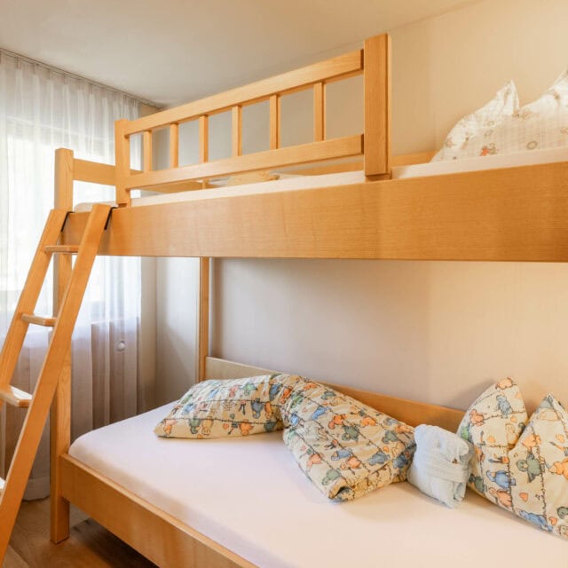 Helles Kinderzimmer mit Hochbett und Kuschelkissen