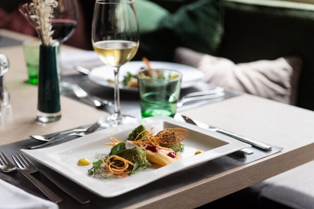 Elegantes Gericht mit Wein und grünem Glas