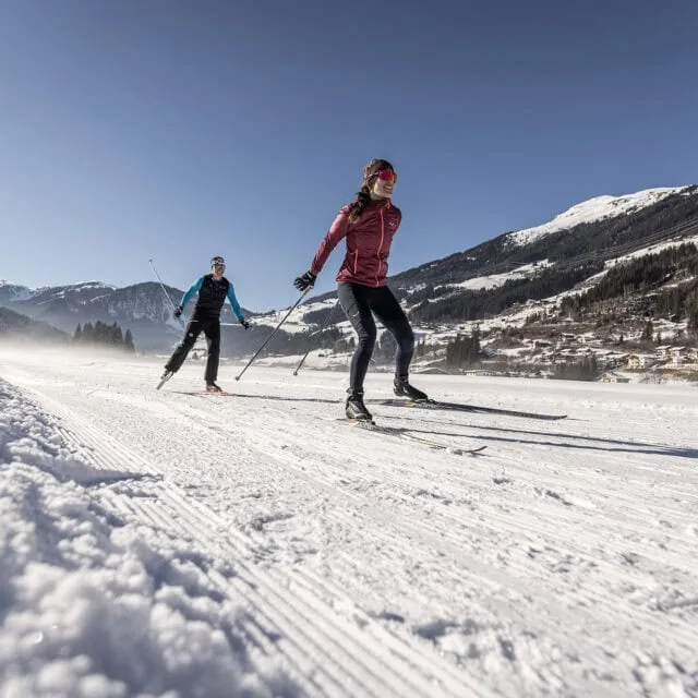 Zwei Menschen beim Skilanglauf im Schnee.